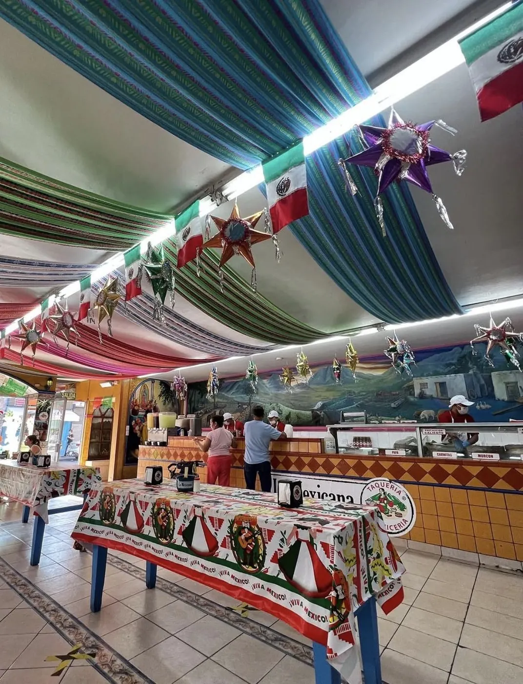 Interior de la Taquería La Mexicana con techo de sarapes, piñatas y el mural de paisaje nuevoleonés al fondo